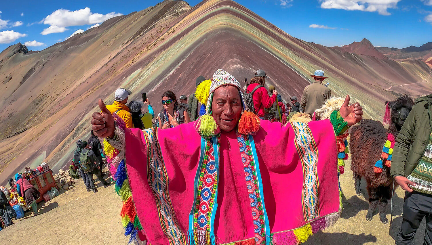 Man in colorful poncho celebrates during a Rainbow Mountain tour