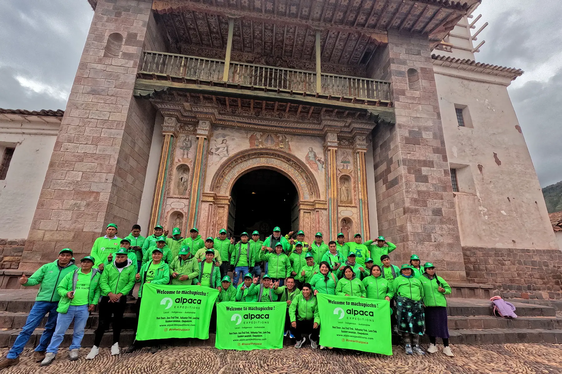 Alpaca Expeditions Green Machine porters group photo in front of a colonial church